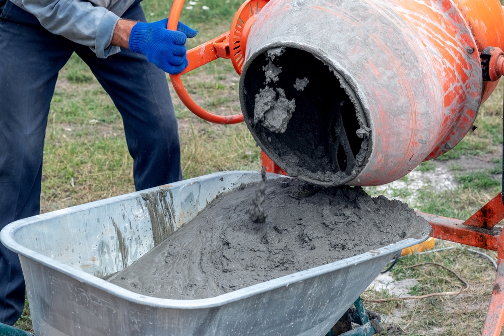A,worker,pours,cement,mortar,,concrete,,from,a,concrete,mixer