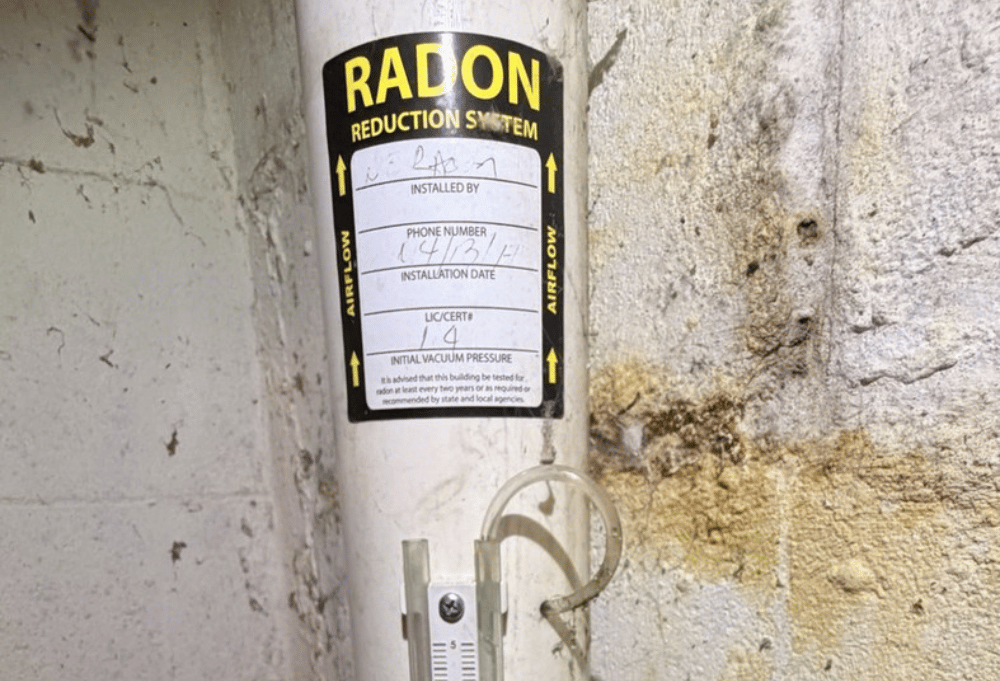 Existing radon mitigation pipe and manometer in a Newburyport Massachusetts basement